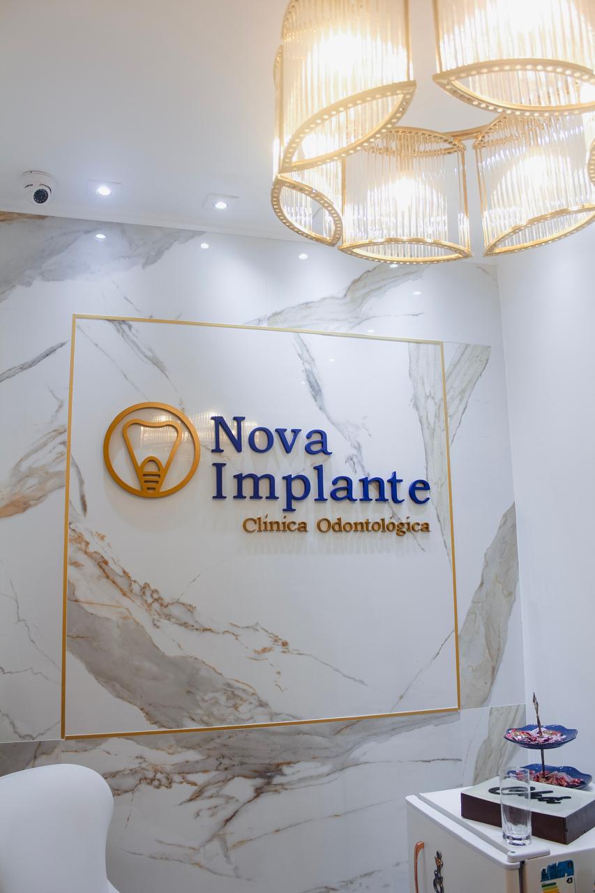 Recepção da clínica Nova Implante com logotipo em parede de mármore